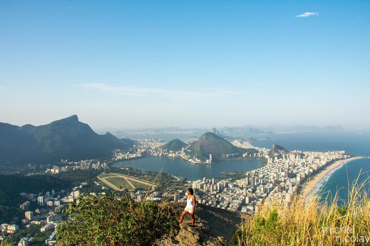 una donna in piedi sulla cima di una montagna che domina una città