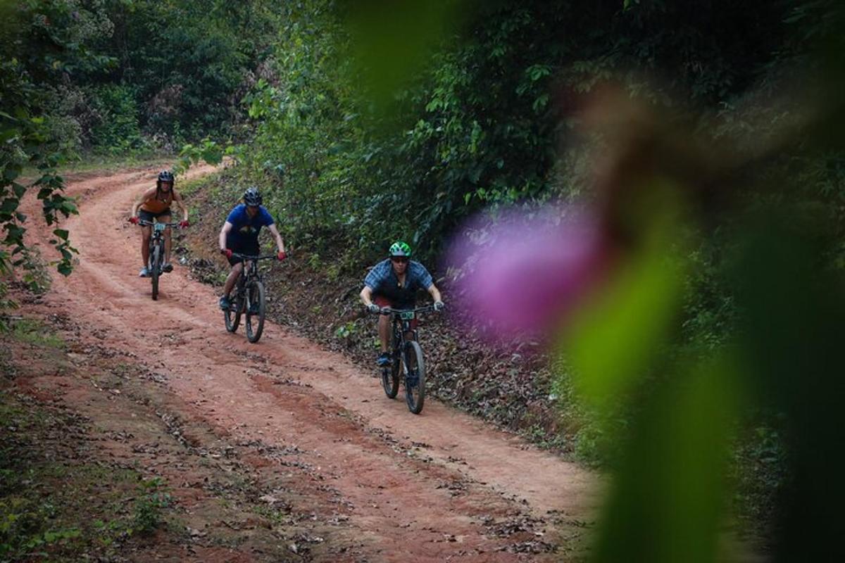 three people riding bikes down a dirt road