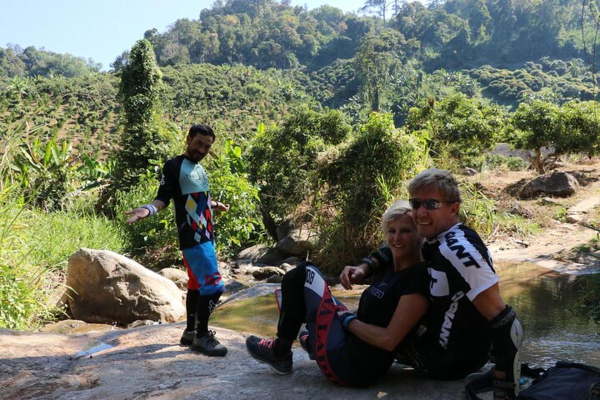 a group of people sitting on a rock near a river