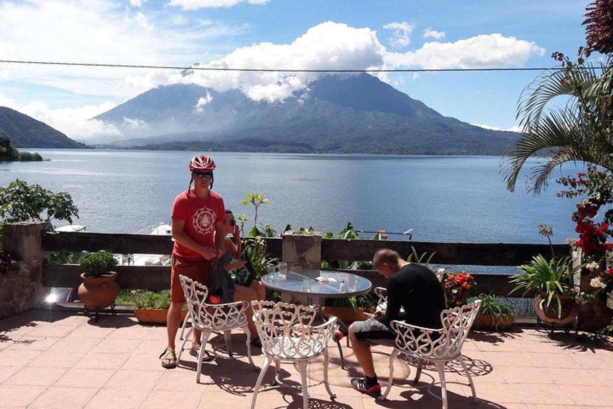 two men sitting at a table with a view of a lake