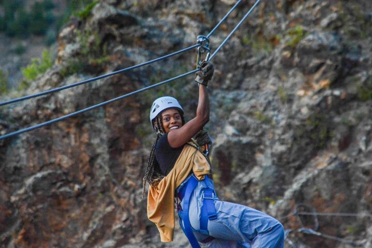 a man is hanging on a rope on a zip line