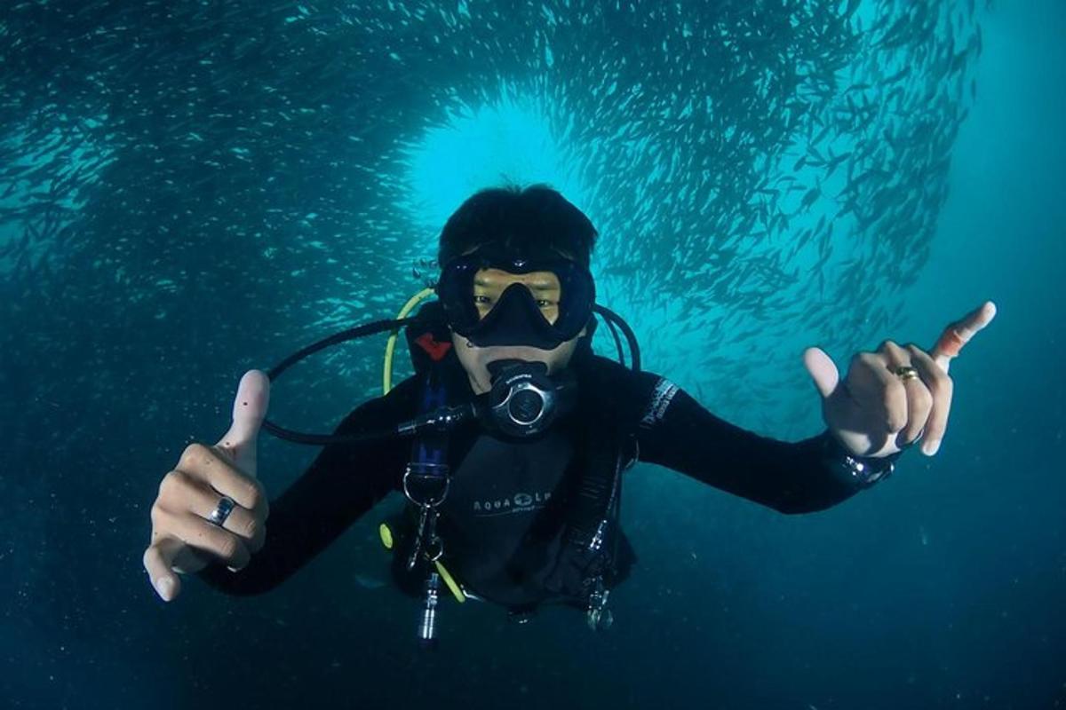Un hombre con traje de buceo y máscara haciendo un gesto de aprobación con el pulgar hacia arriba.