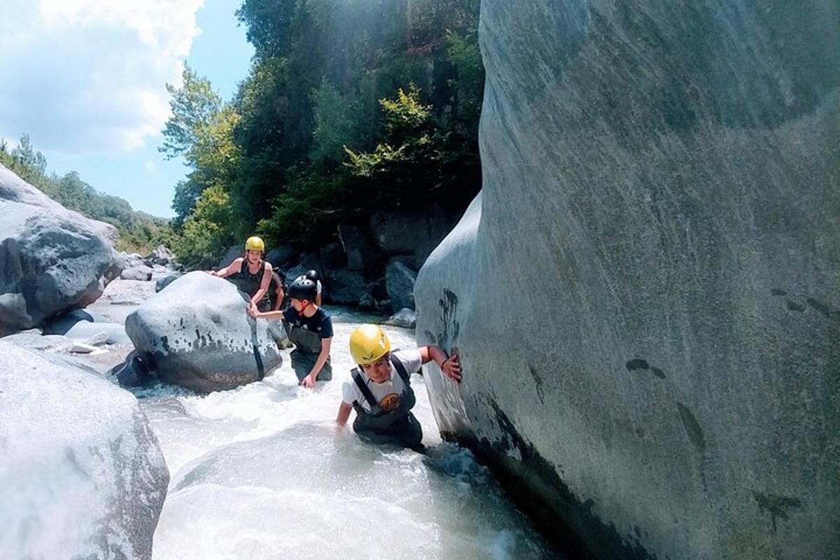 tiga orang di dalam air di sungai dengan batu