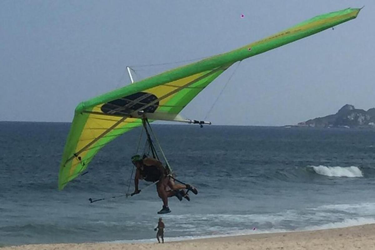 um homem empinando uma pipa na praia