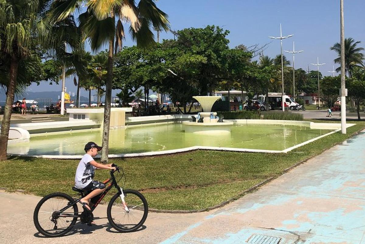 a boy riding a bike in front of a fountain