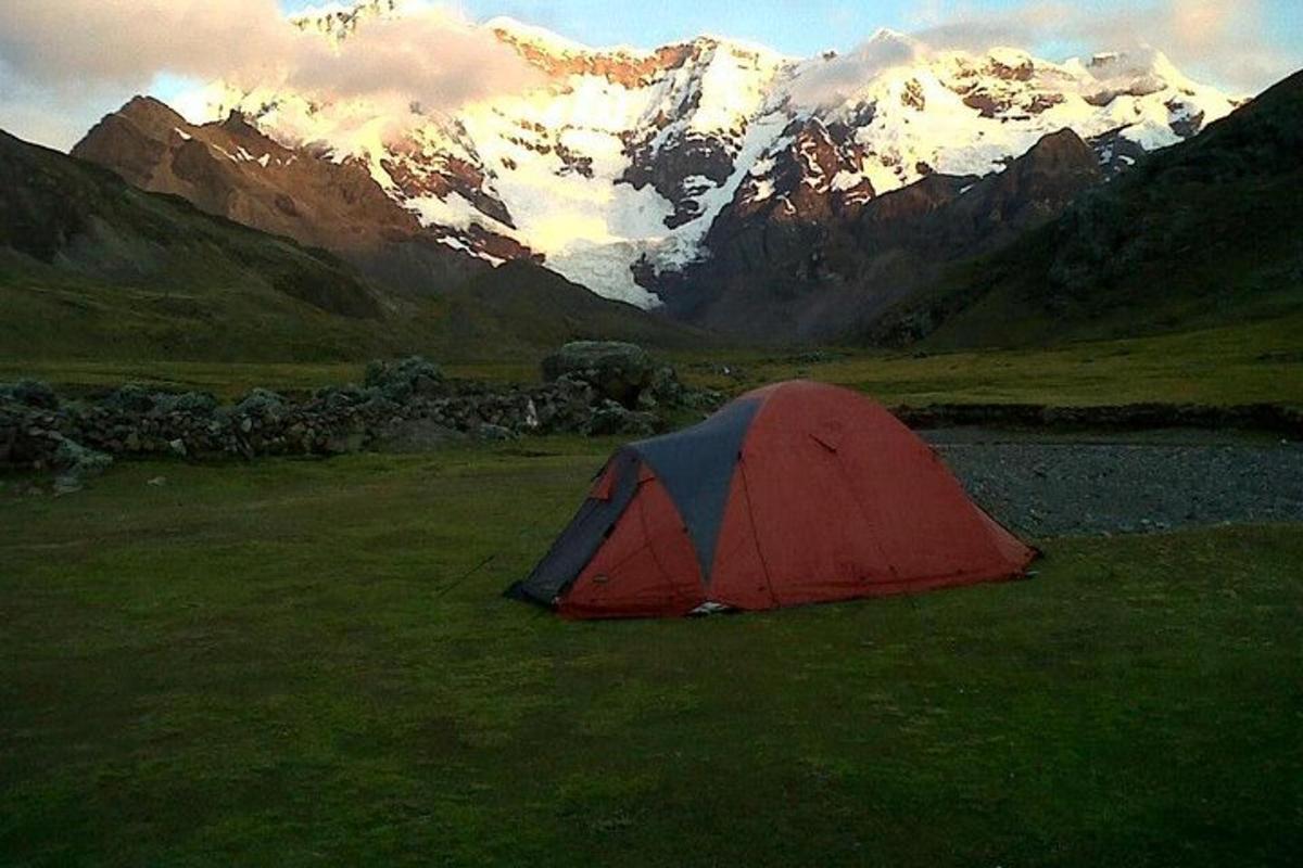 uma tenda vermelha e azul em um campo com montanhas