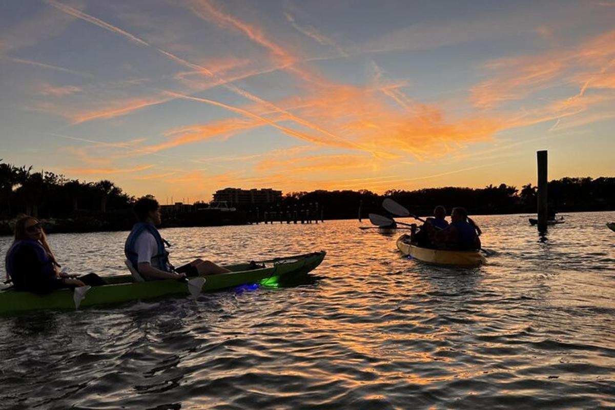 un grup de oameni în canoe pe apă la apus