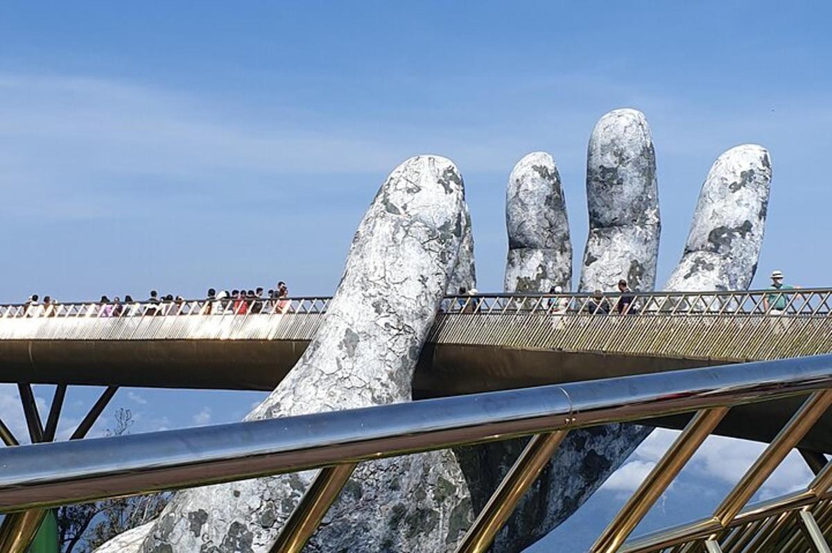 a bridge in front of a statue of two hands