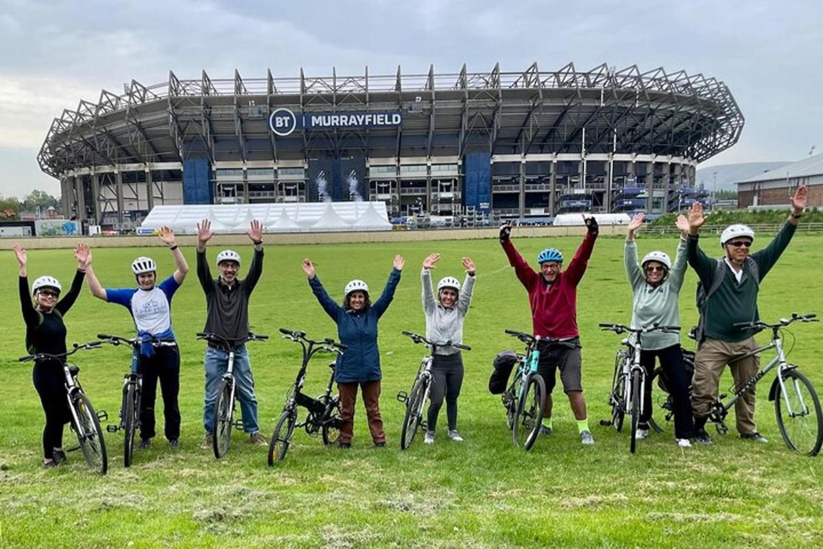 un grup de oameni care stau cu bicicletele în fața unui stadion