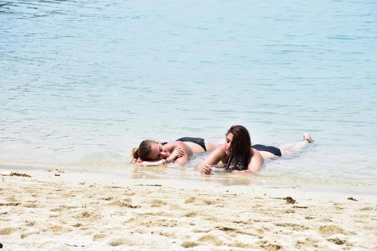 two women laying in the water on the beach