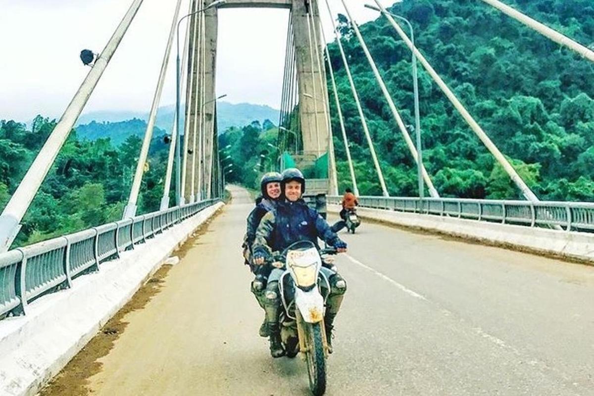 zwei Personen, die auf einem Motorrad auf einer Brücke fahren