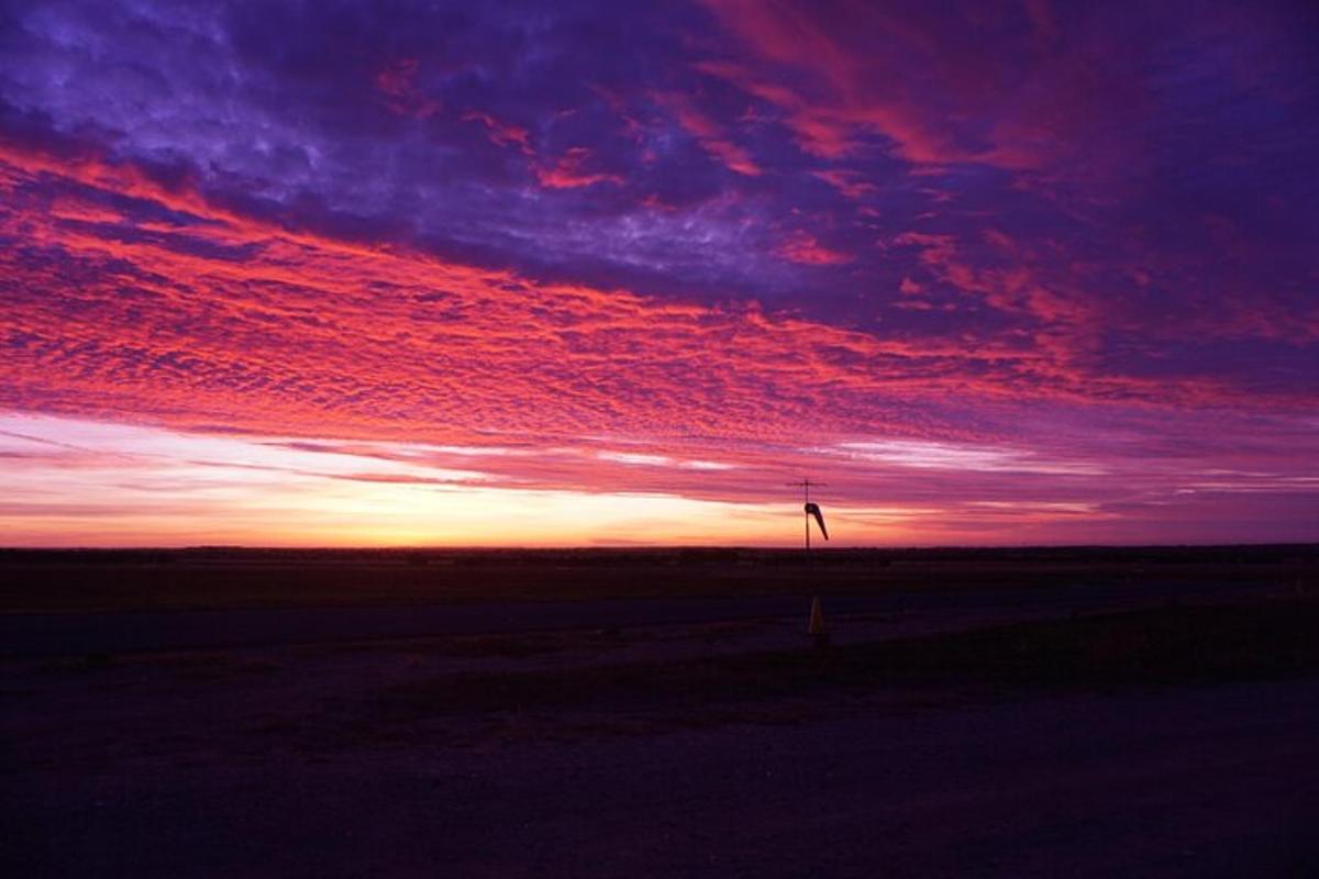 a sunset with a windmill in the middle of a field