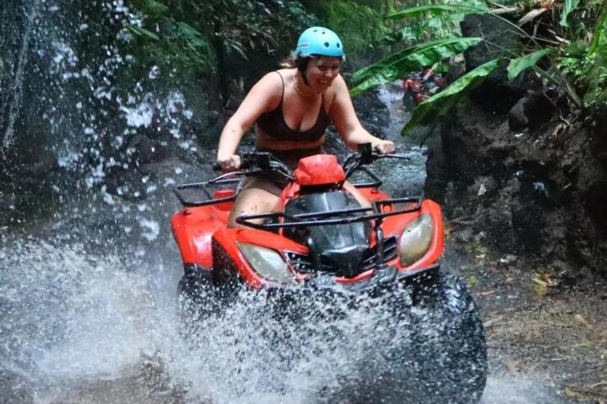 seorang wanita mengendarai ATV melewati air terjun