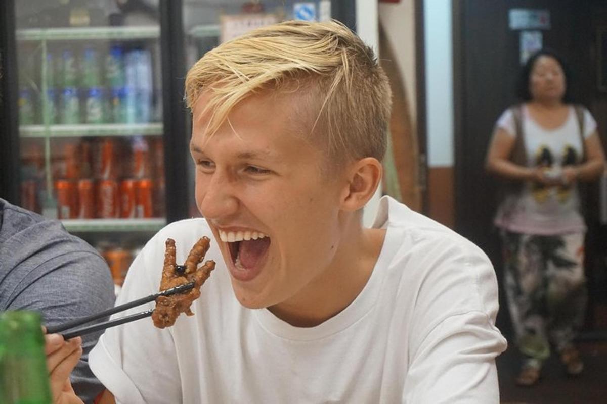 꼬치에 음식을 꿰어 입을 벌리고 있는 소년
