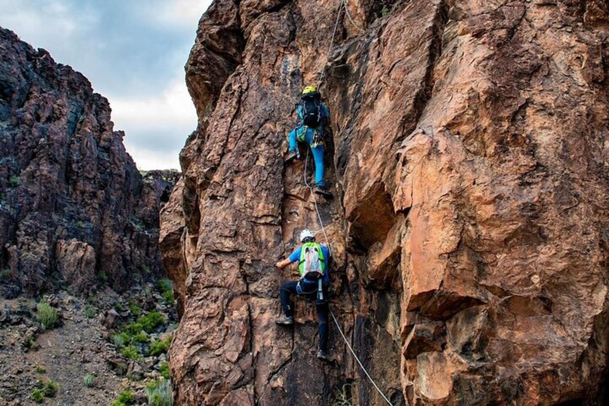 due persone che scalano il fianco di una montagna