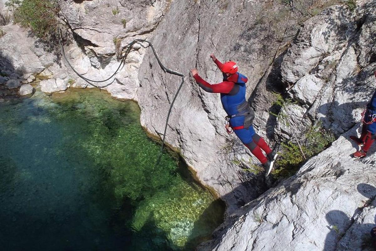 a man climbing a rock wall next to a body of water
