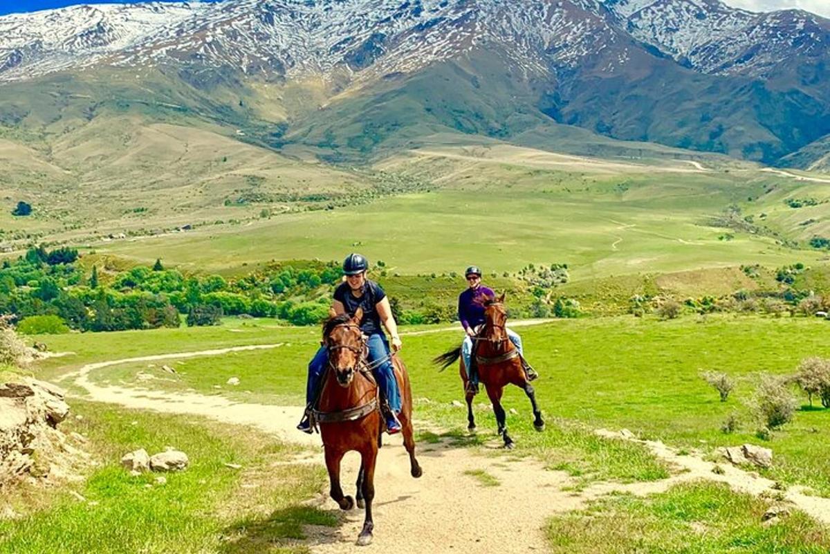 duas pessoas andando a cavalo em uma estrada de terra