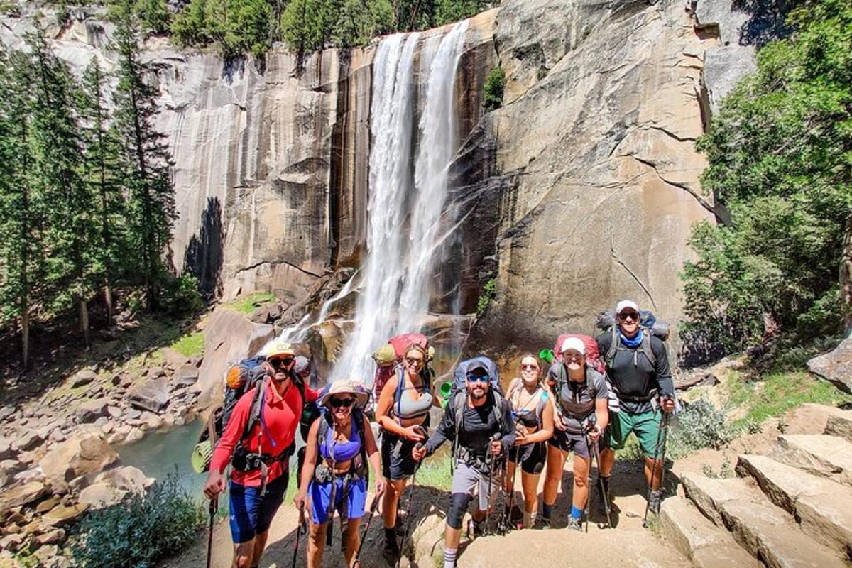 a group of people hiking in front of a waterfall
