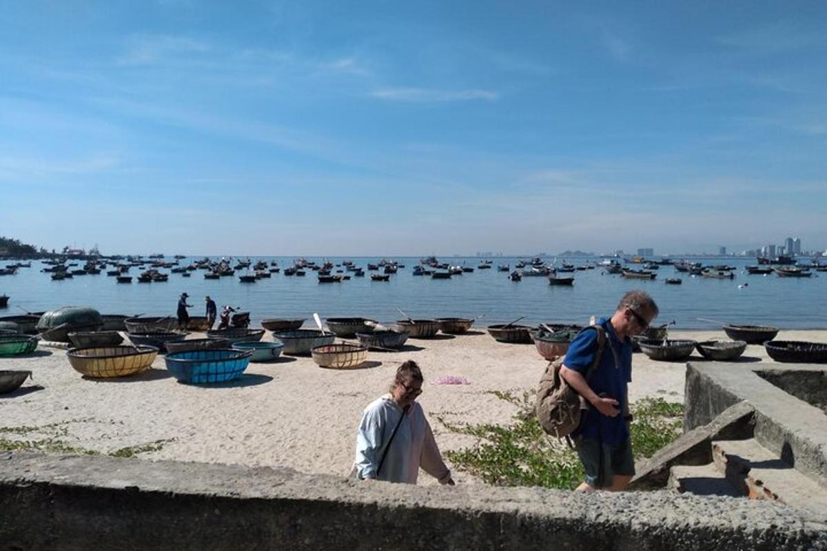 skupina ljudi, ki stojijo na plaži s čolni v vodi