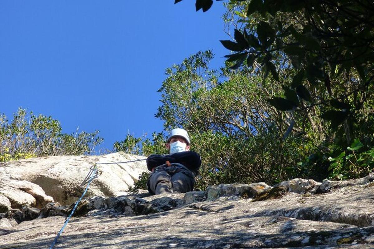 moški, ki sedi na vrhu skale z nahrbtnikom