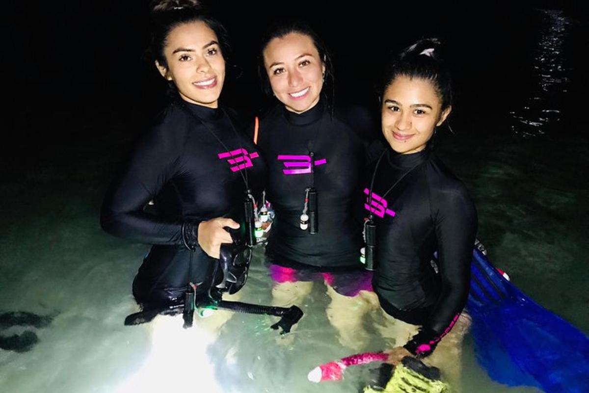 Tres personas paradas en el agua en el océano.