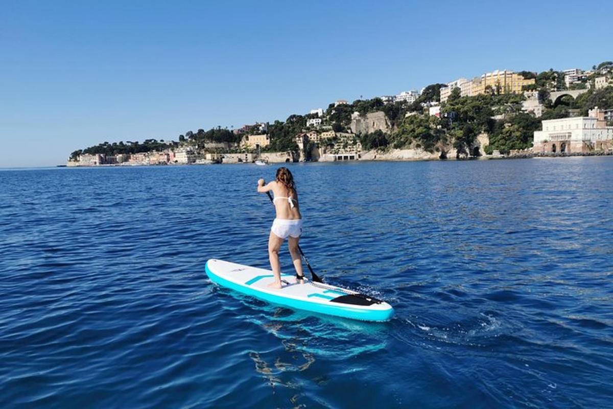 kobieta stojąca na desce surfingowej w wodzie