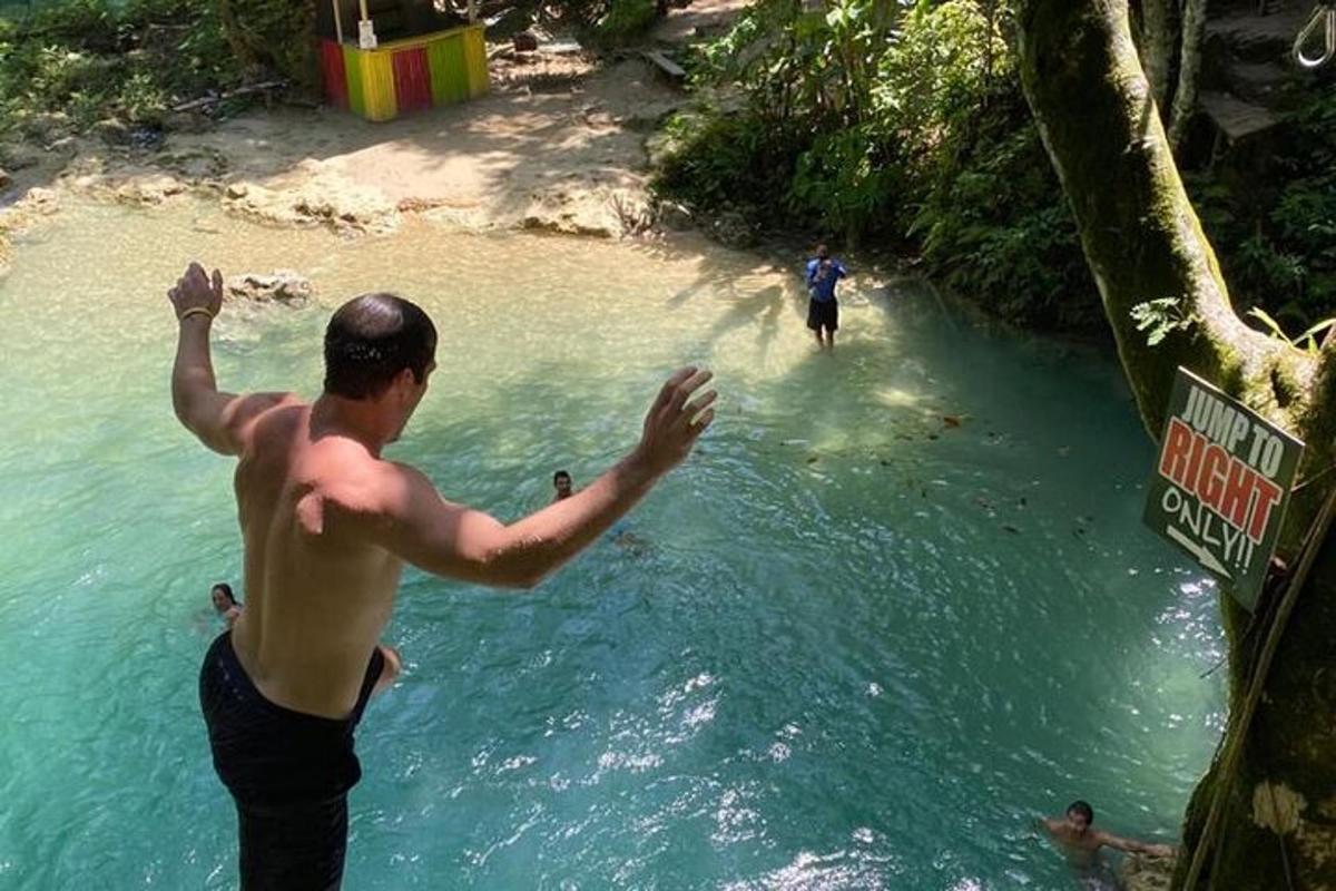 Un hombre parado en un río con los brazos en alto.