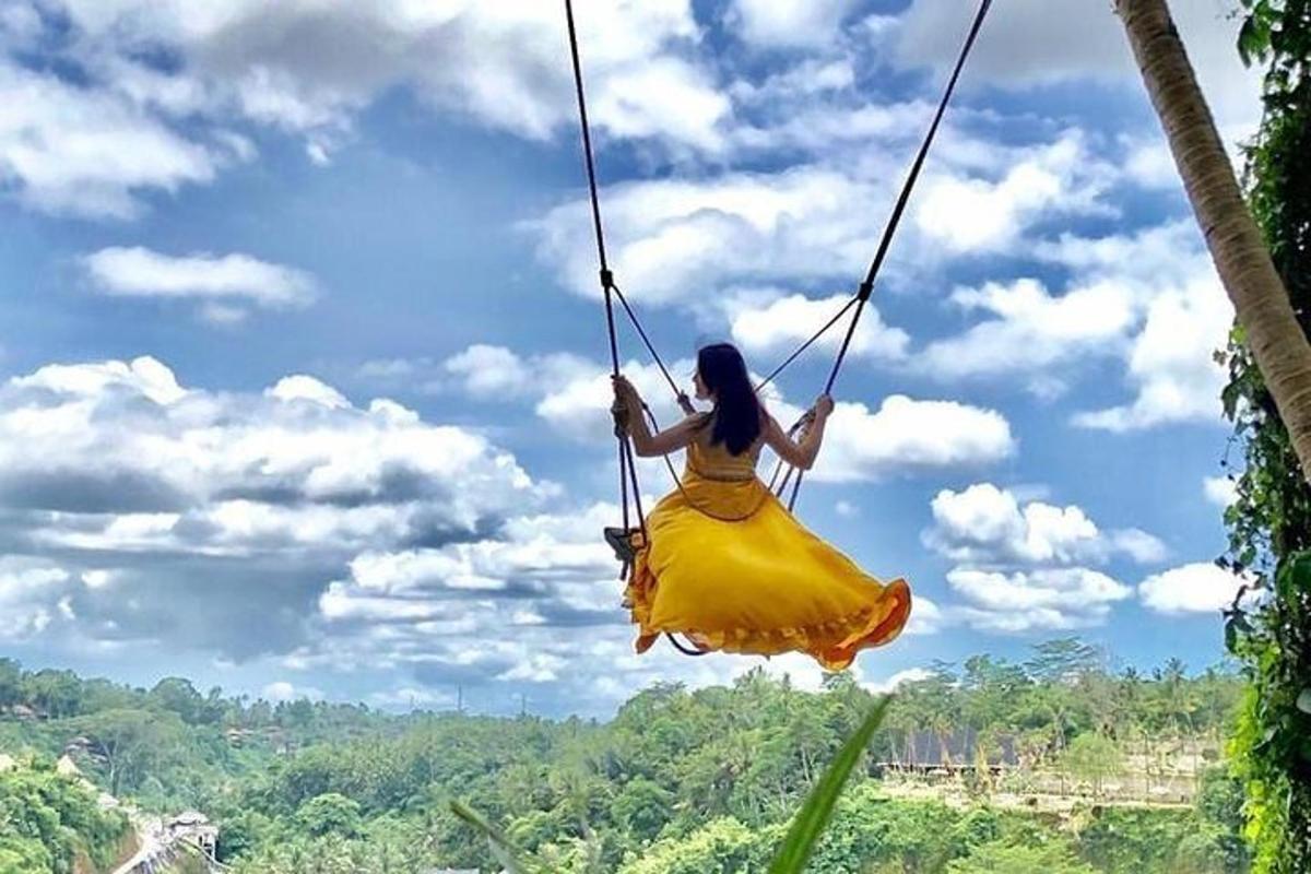 Una mujer con un vestido amarillo balanceándose en un columpio