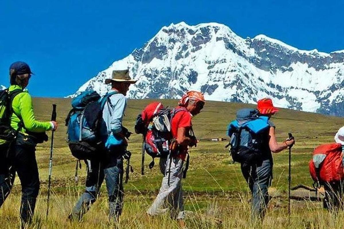 un gruppo di persone con zaini che camminano di fronte a una montagna