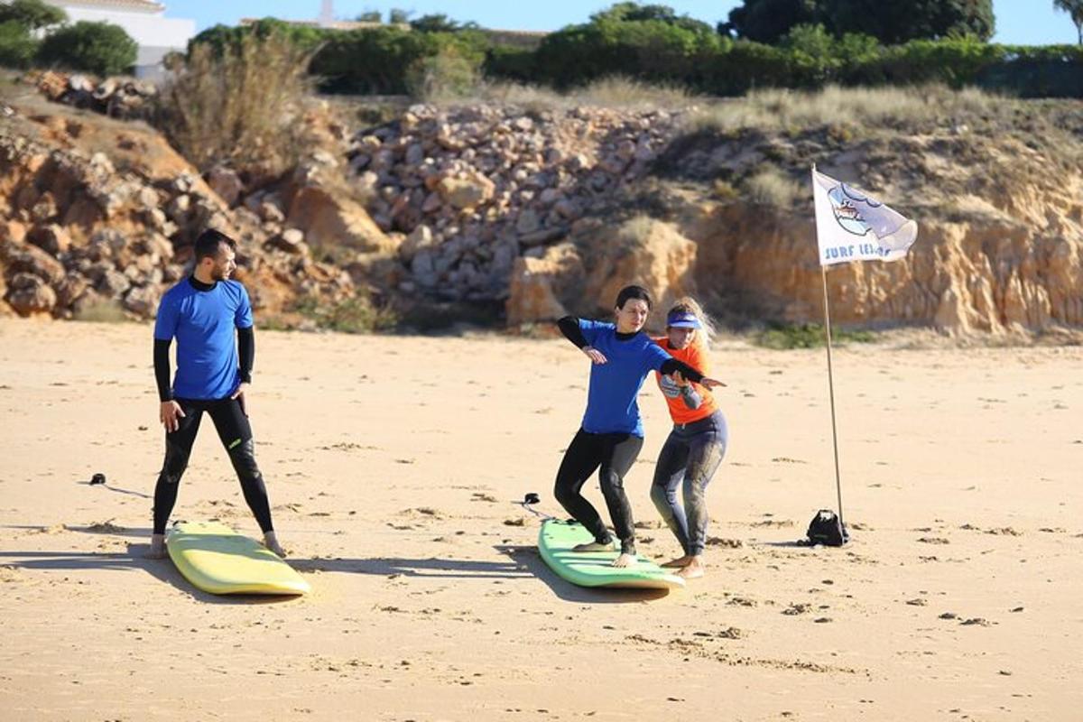 drei Personen stehen auf Surfbrettern am Strand