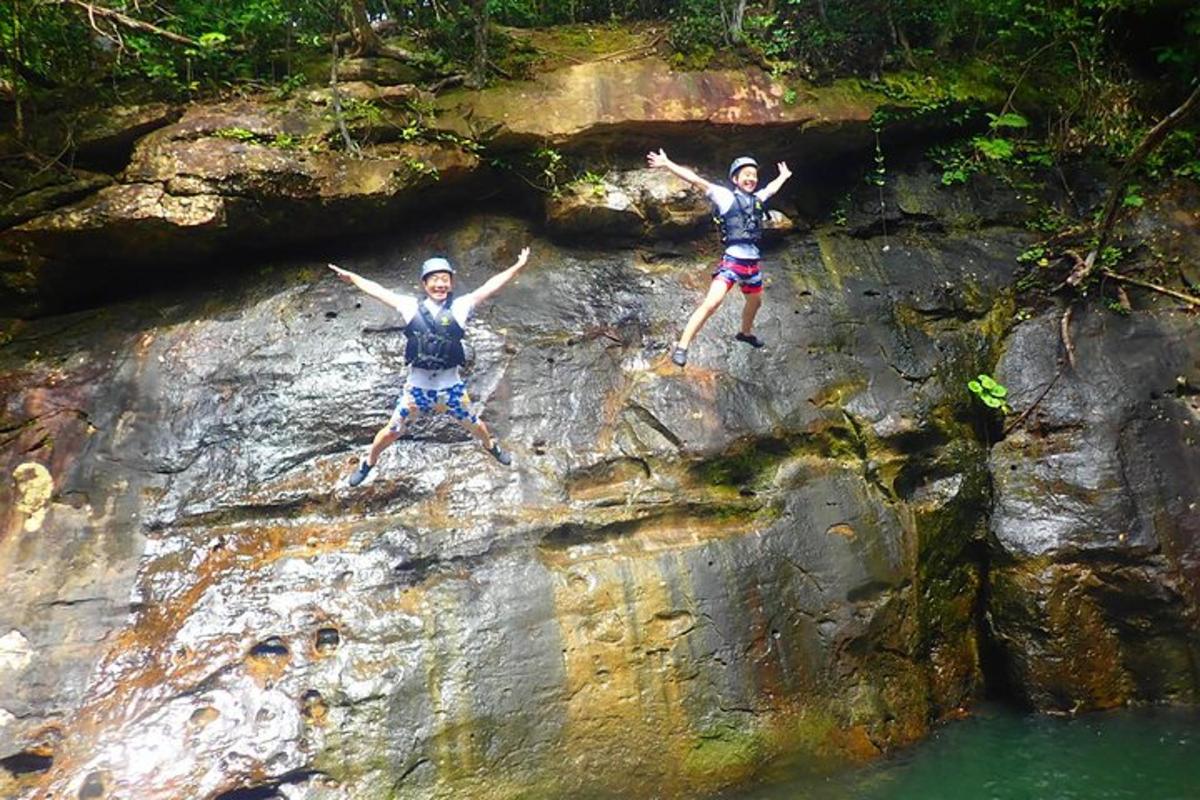 due persone che saltano da una roccia in acqua