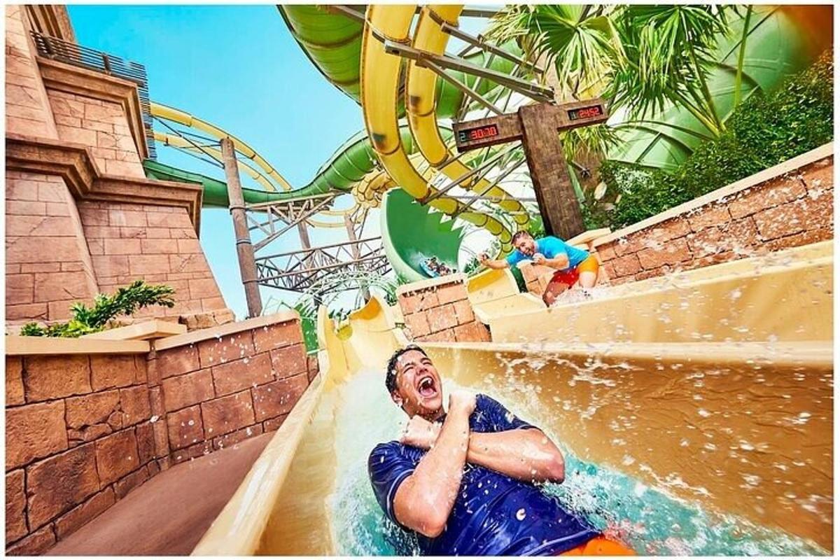 Un hombre montando en un tobogán de agua en un parque acuático.