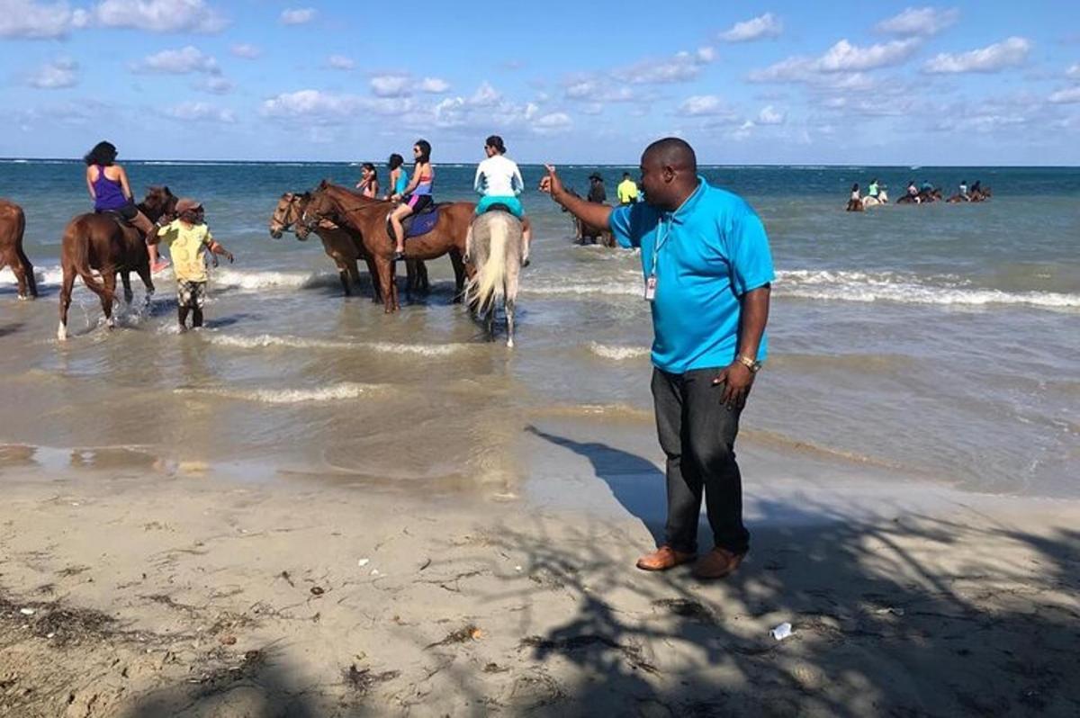 um homem parado na praia com um grupo de cavalos