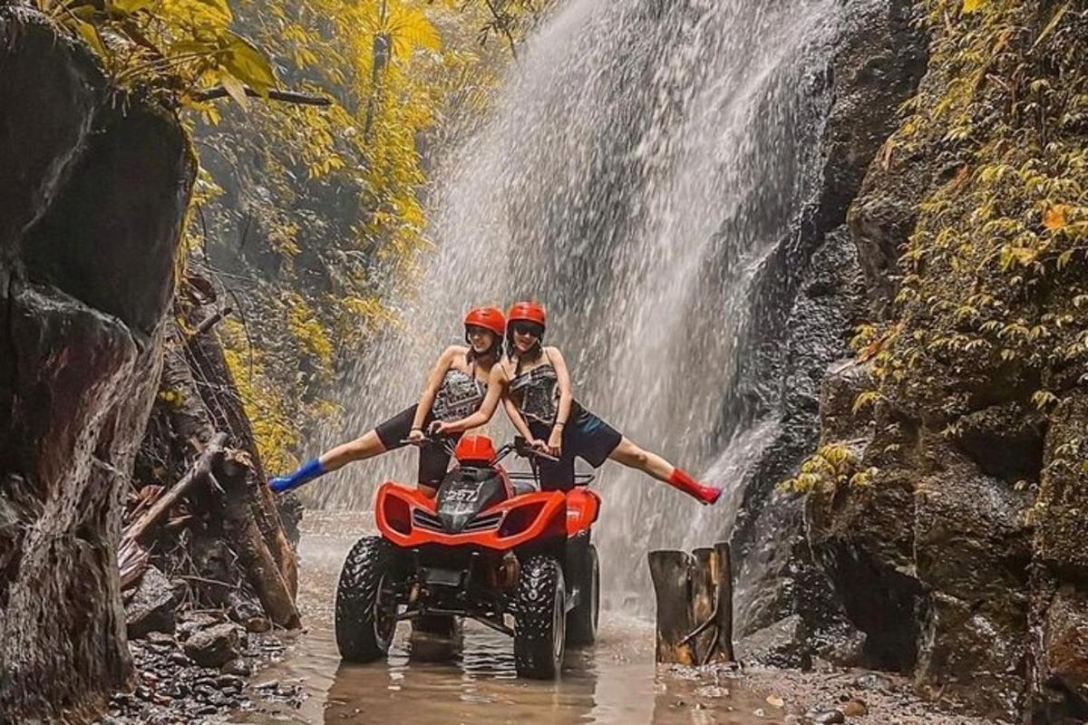 Două persoane pe un ATV în fața unei cascade