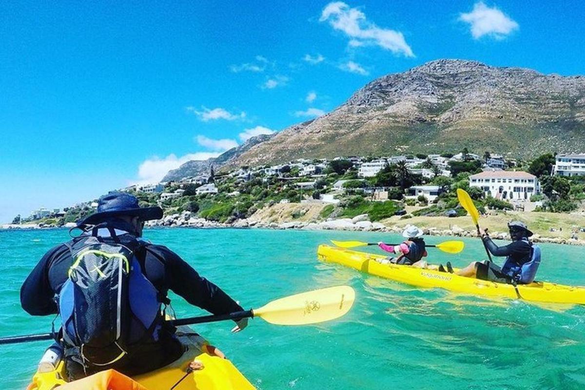 three people kayaking in the water with a mountain in the background