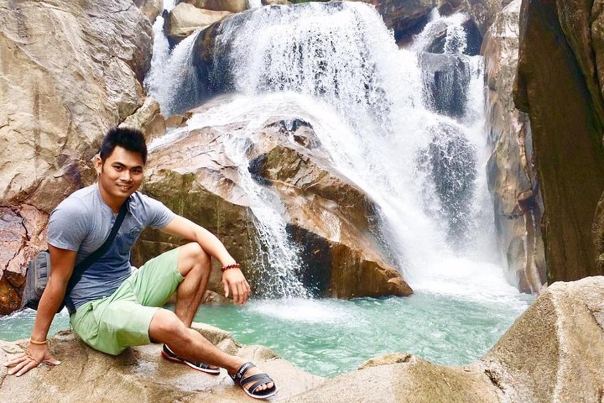 un uomo seduto sulle rocce di fronte a una cascata