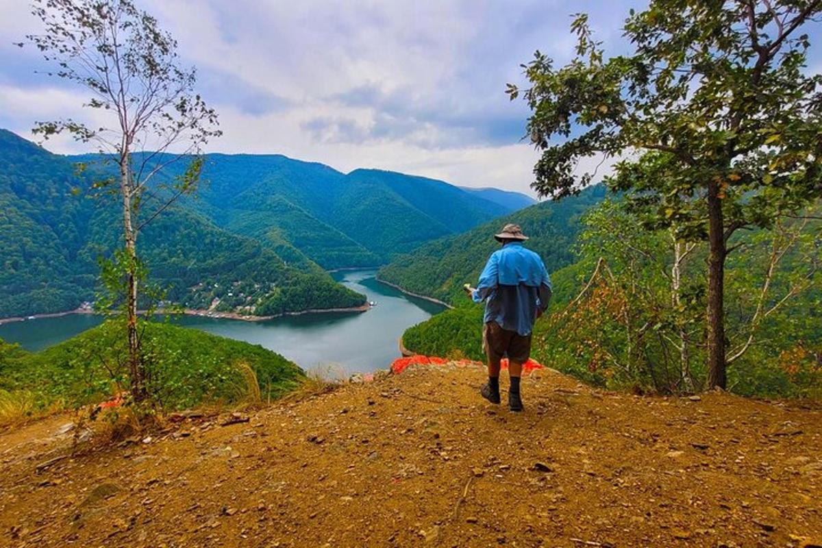 un uomo in piedi sulla cima di una collina che domina un fiume