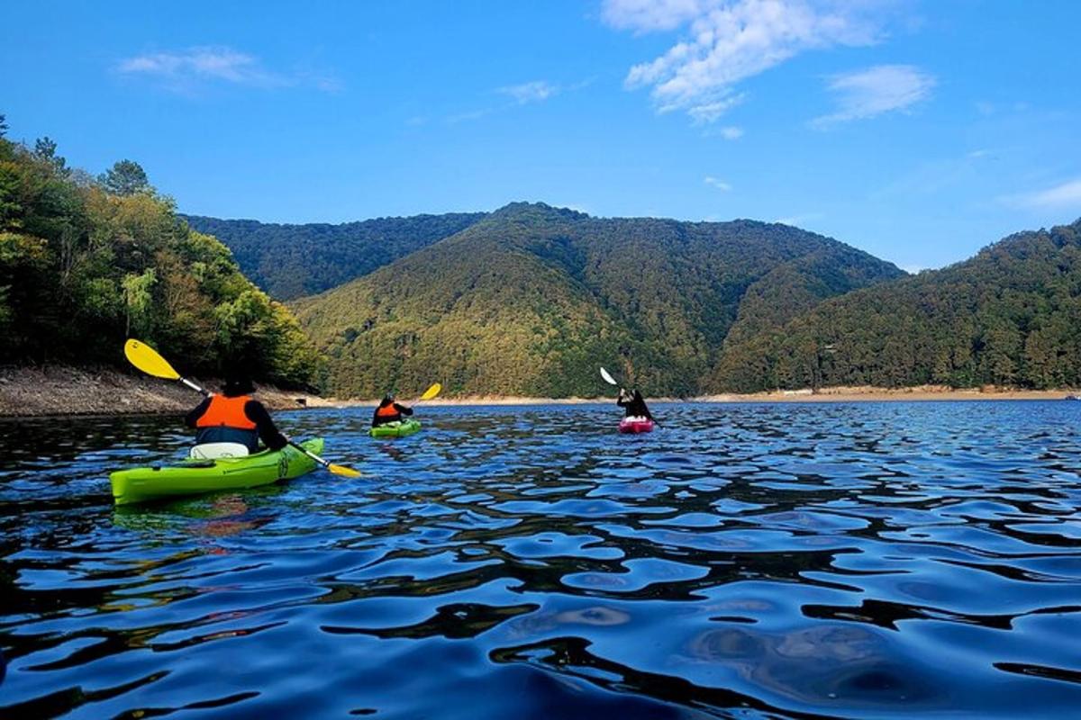 tre persone che fanno kayak su un lago con le montagne sullo sfondo
