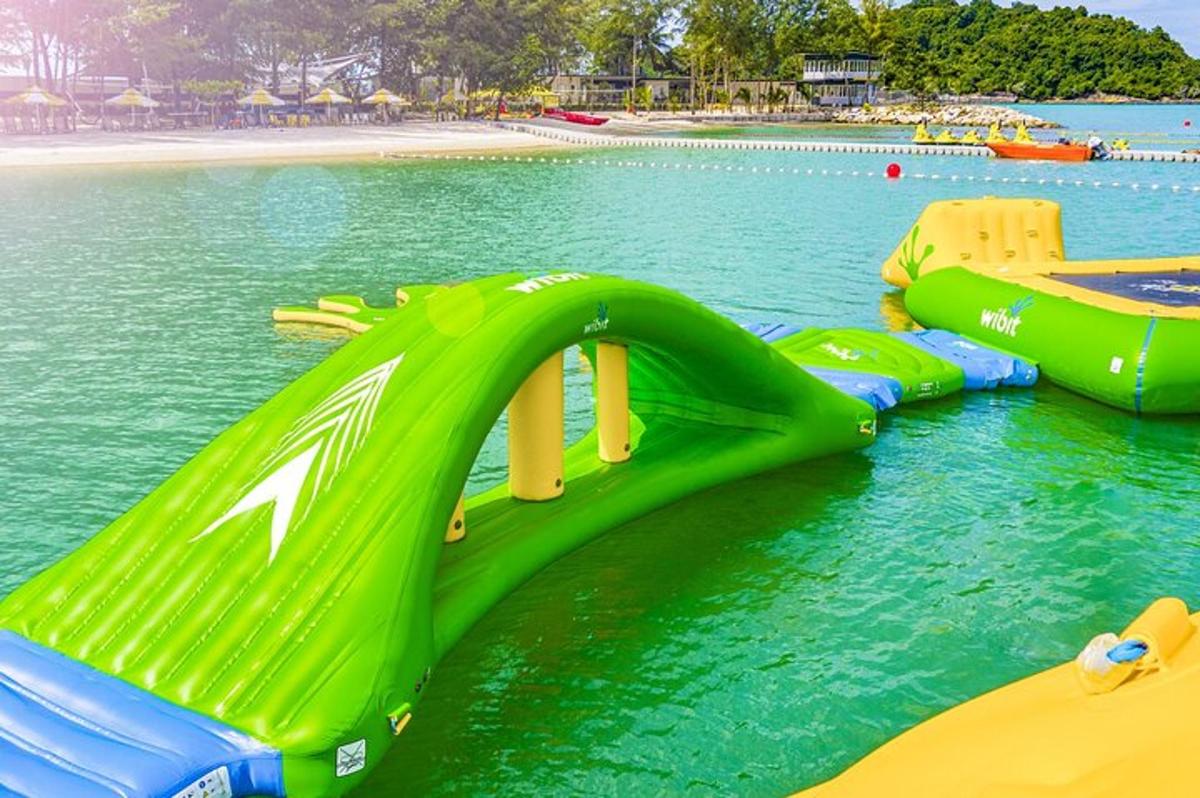 a green water slide in the water at a beach
