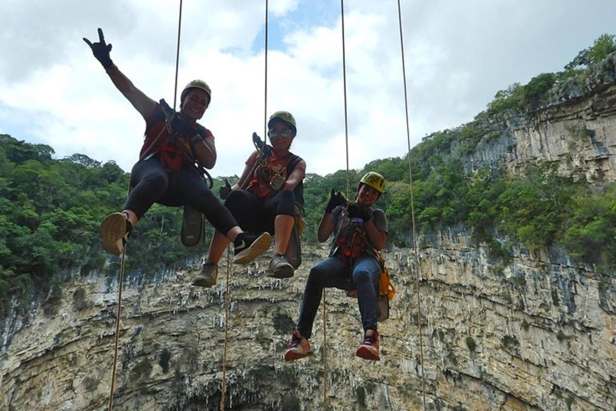 three people are hanging from ropes on a cliff