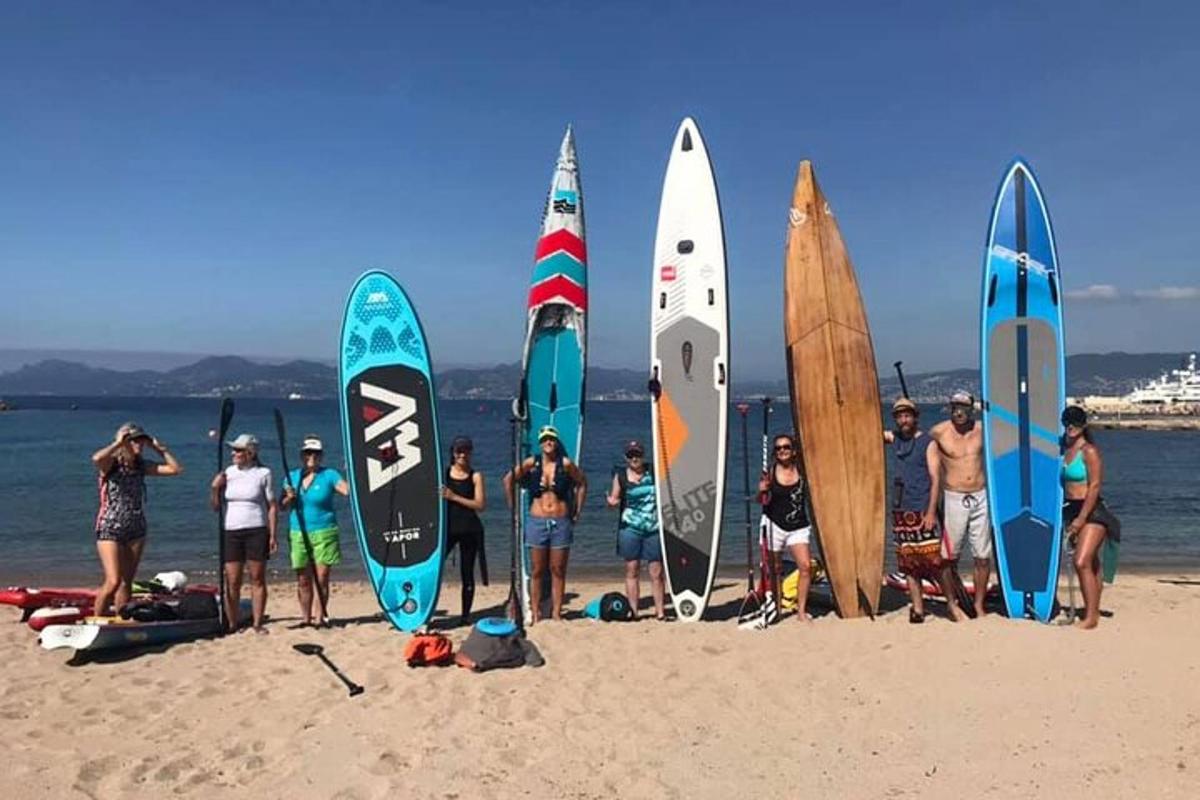 sekelompok orang berdiri di pantai dengan papan selancar