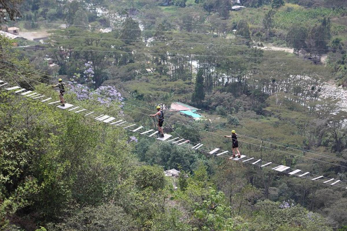 trije ljudje hodijo po ziplineu čez hrib
