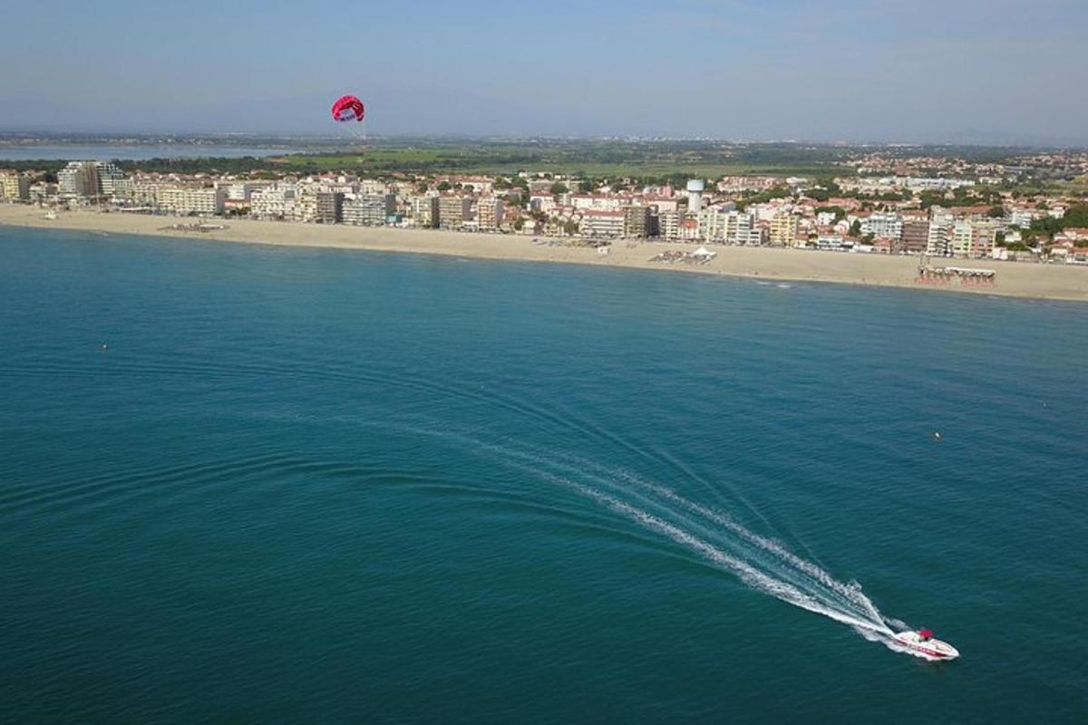 a boat in the water with a kite flying over a beach