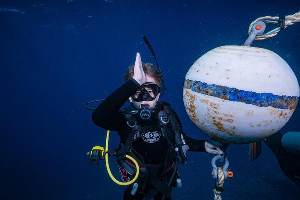 ein Mann im Taucheranzug mit einer Kamera im Wasser