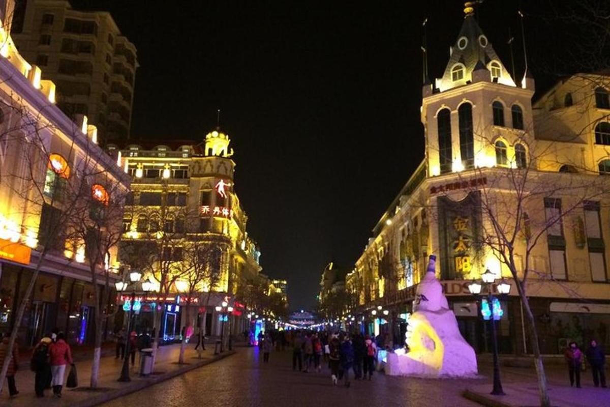 uma rua da cidade à noite com uma grande escultura de boneco de neve