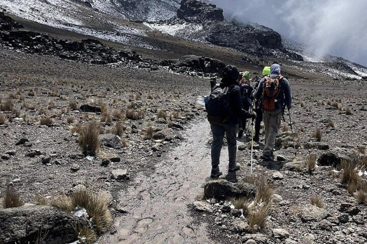 duas pessoas caminhando em uma trilha de terra nas montanhas