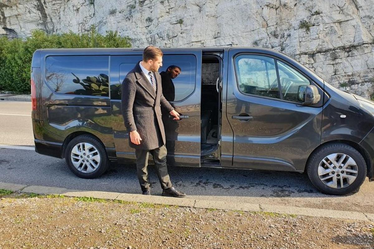 un home amb vestit dret al costat d'una furgoneta