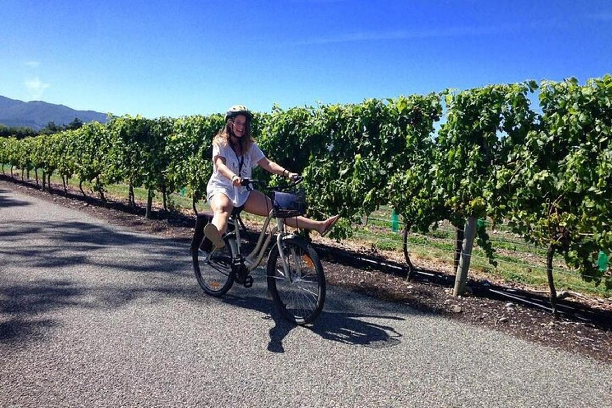 a woman riding a bike in front of a vineyard