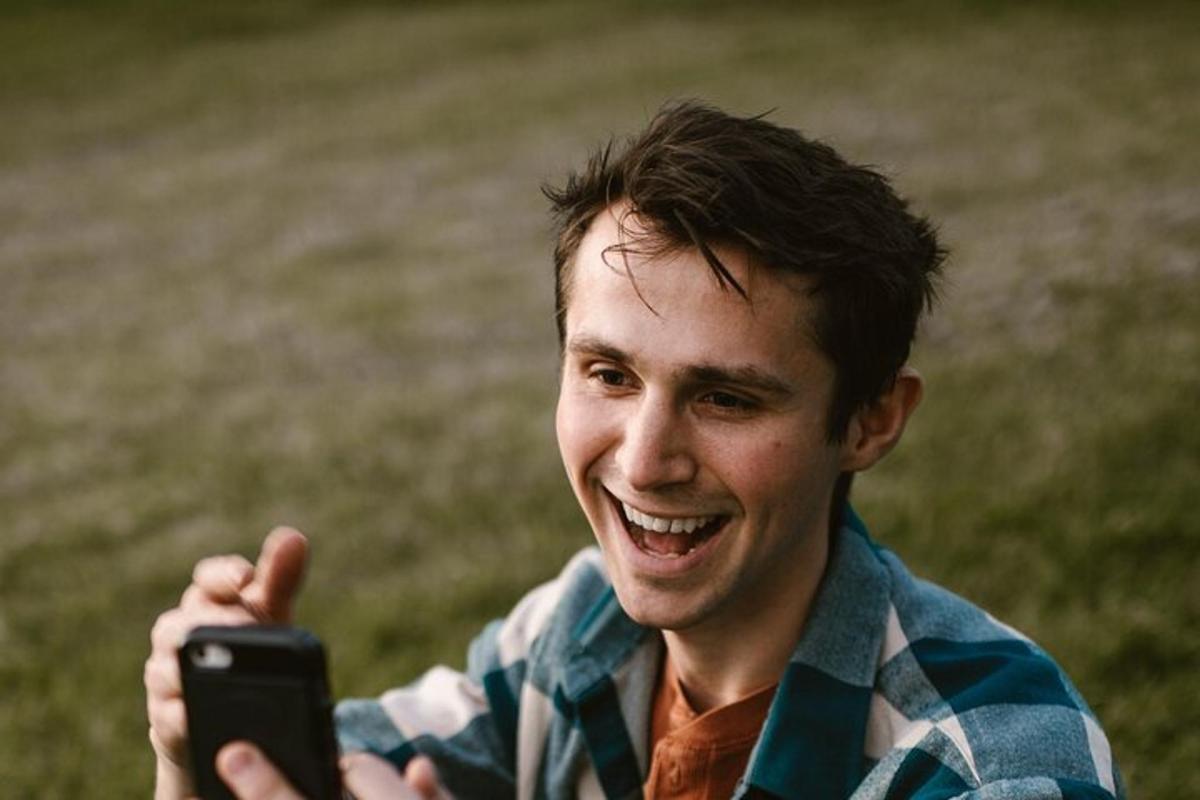 muž se usmívá a drží mobilní telefon