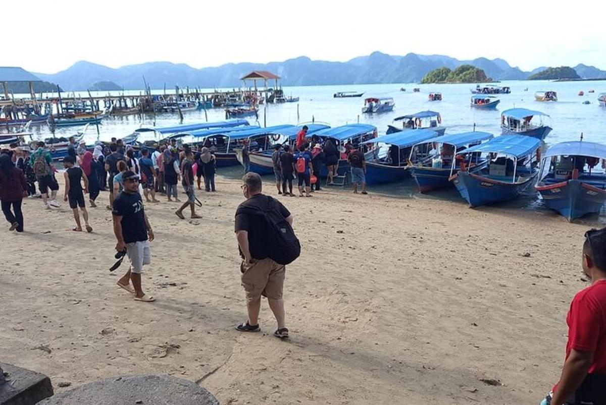 Un grupo de personas de pie en una playa con barcos.